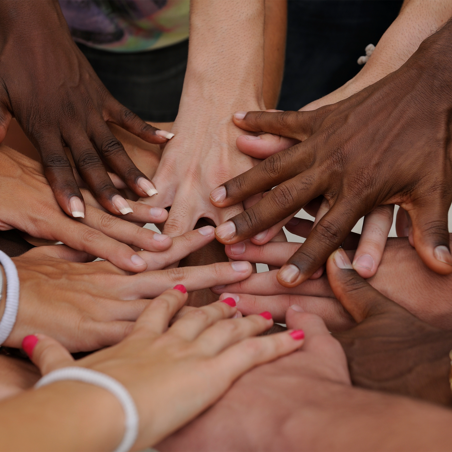 Diverse group of hands united in a circle, symbolizing feminist solidarity, racial justice, and collective power.